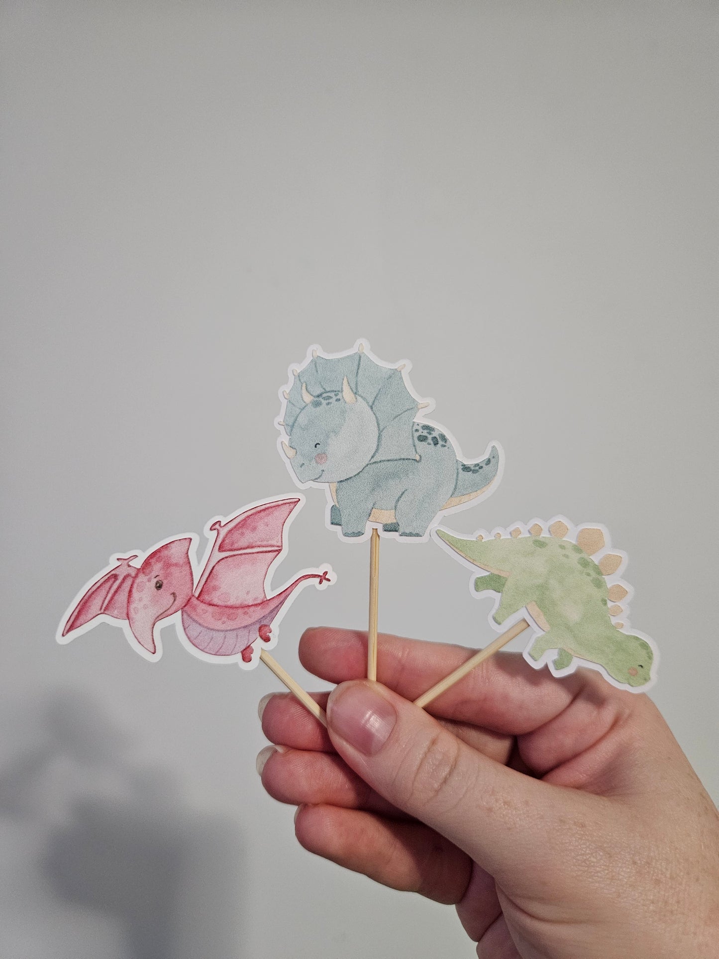 3 dinosaur cupcake toppers on white background