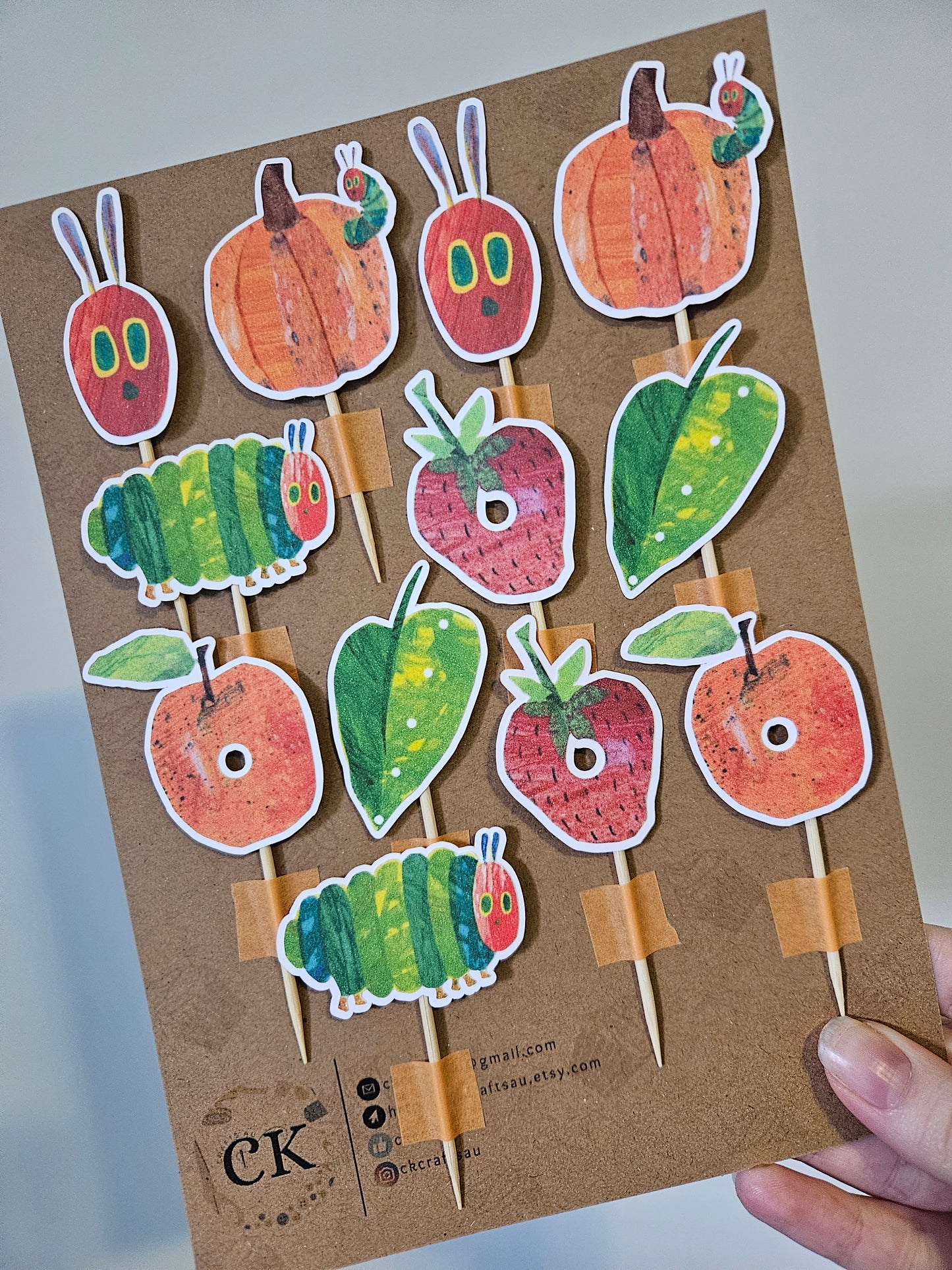 Cardboard backing with caterpillar and fruit pieces held by a hand
