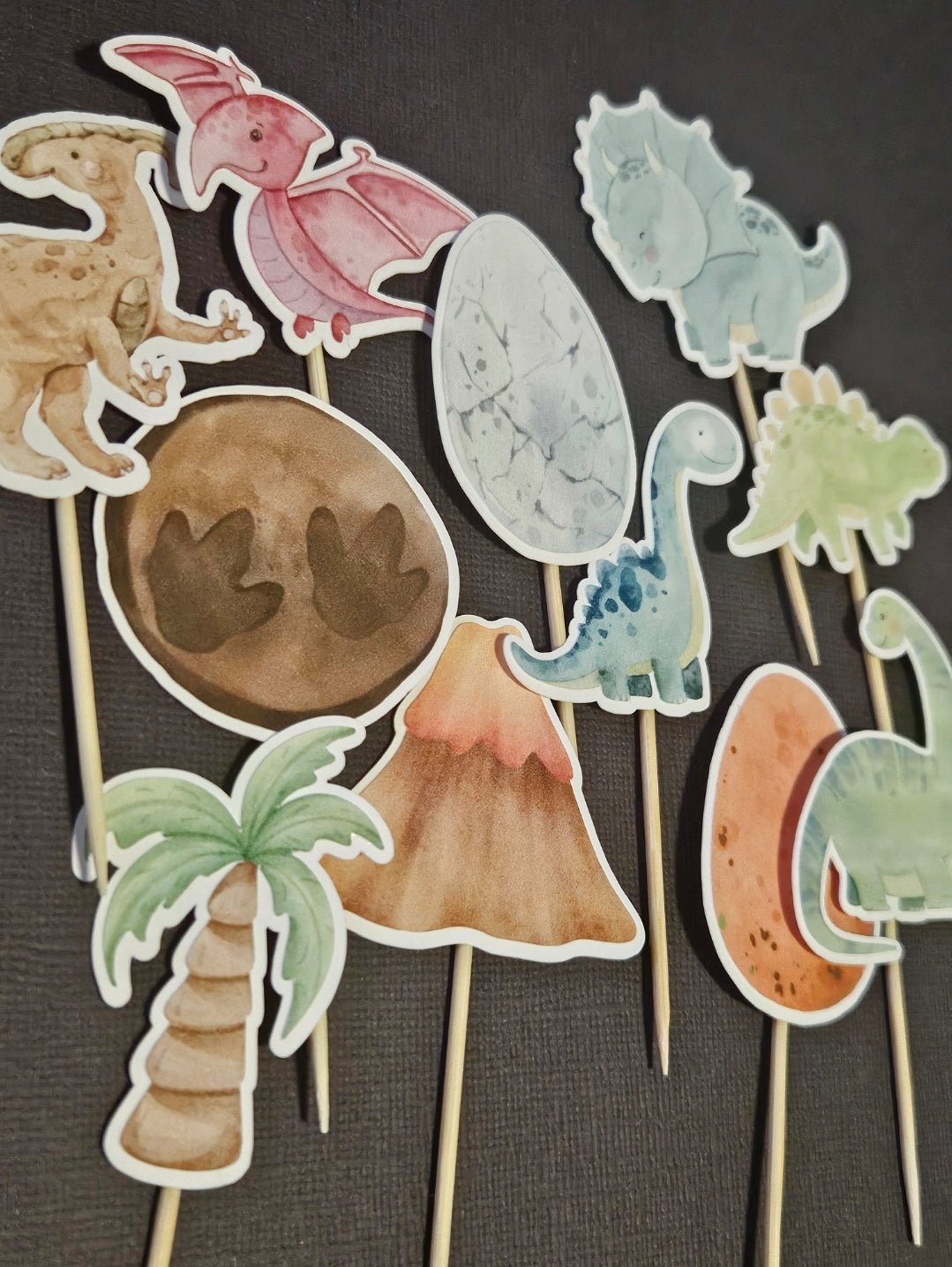 display of dinosaur cupcake toppers on black background