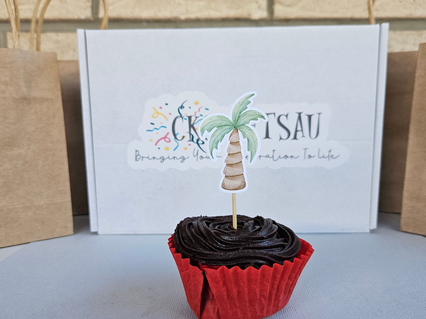 Chocolate cupcake with red wrapper with tree cupcake topper in front of white branded box