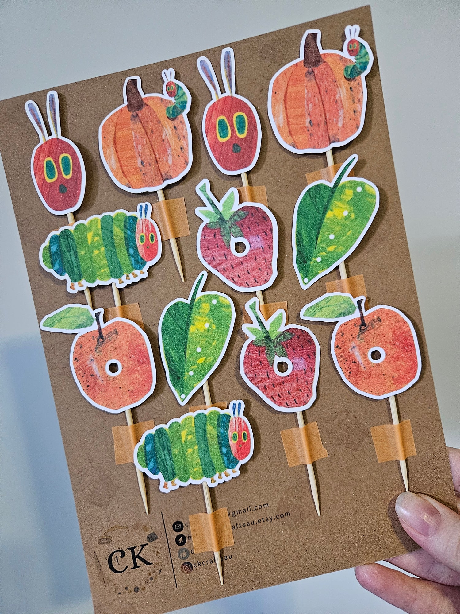 Cardboard backing with caterpillar and fruit pieces held by a hand