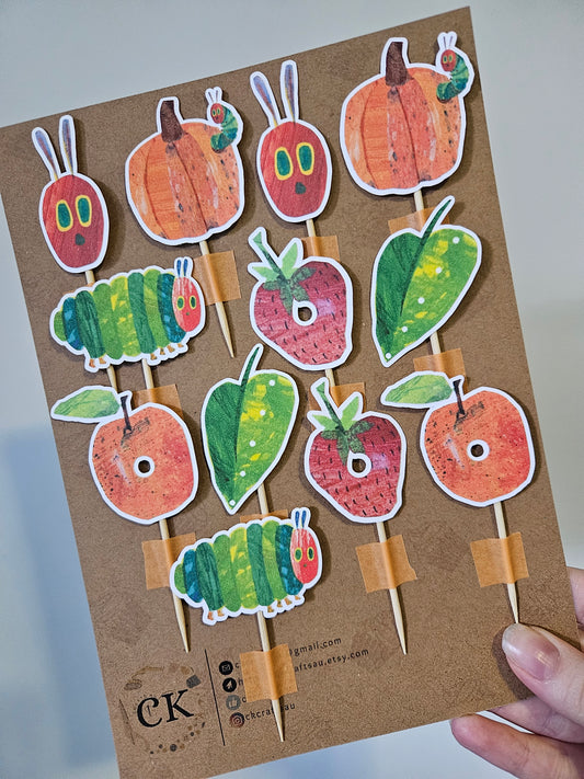 Cardboard backing with caterpillar and fruit pieces held by a hand